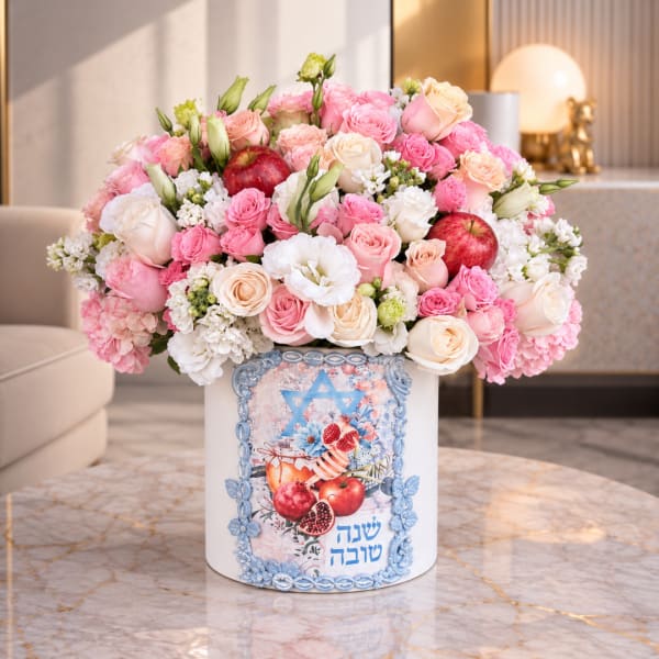 Pink and white rose arrangement in a decorated white box with apples
