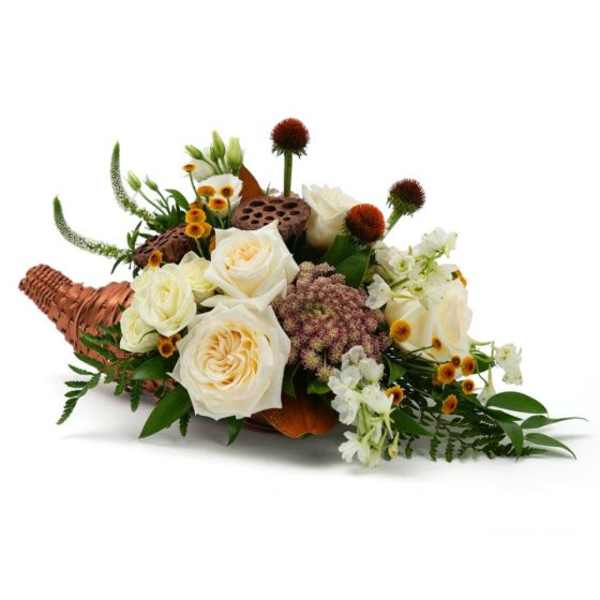 Cornucopia centerpiece with cream roses, white blossoms, and small yellow flowers in a woven horn basket.