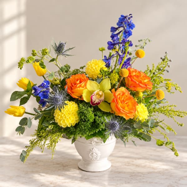 Colorful mixed flower arrangement in a white pedestal vase