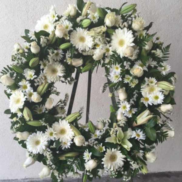 White floral wreath with daisies, roses, and lilies