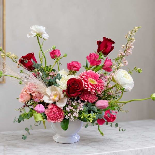 Mixed pink and red flower arrangement in a white vase