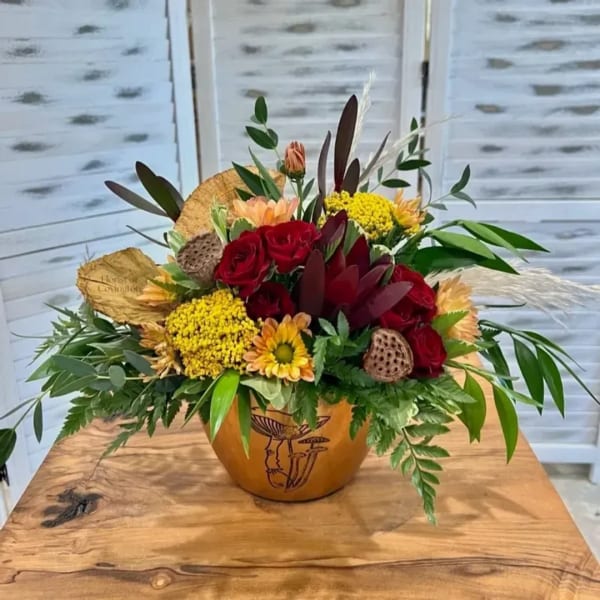 Mixed bouquet of red roses and yellow flowers in a decorative vase