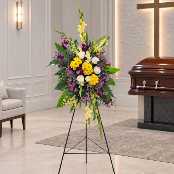 Standing floral spray with yellow, white, and purple flowers on an easel