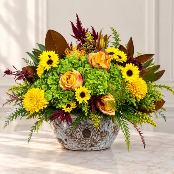 Yellow flowers and orange roses arranged in a rustic ceramic bowl