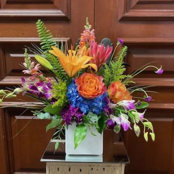 Colorful mixed flower arrangement in a white square vase