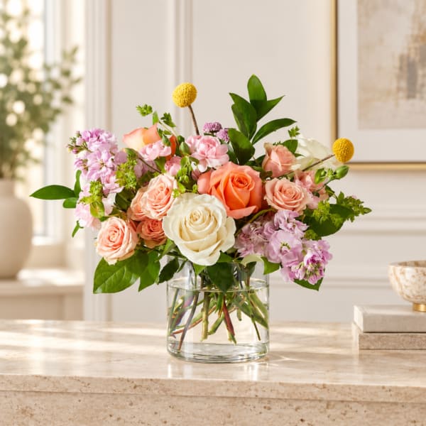 Mixed bouquet of roses and pink flowers in a clear glass vase