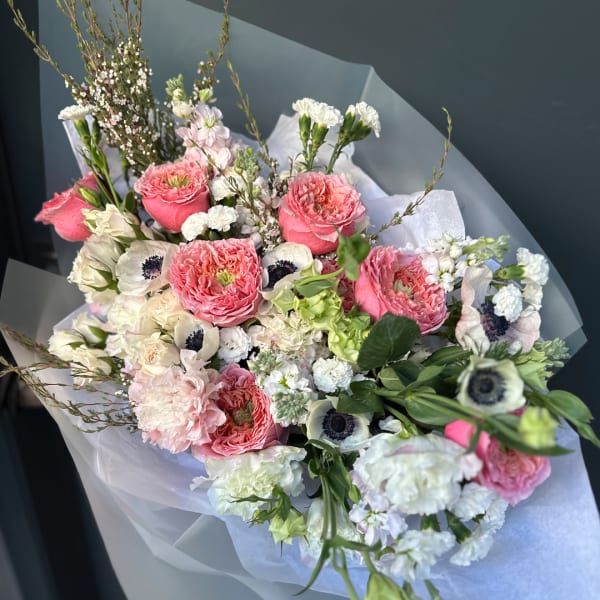 Bouquet of pink and white flowers wrapped in pale paper
