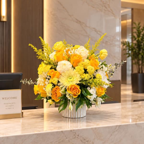 Yellow and white flower arrangement in a ribbed vase on a marble counter