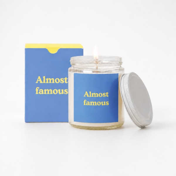 Lit candle in a glass jar with a blue label and matching box
