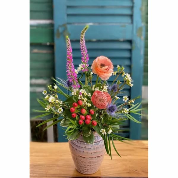 Mixed flower arrangement in a ceramic vase with pink and peach blooms