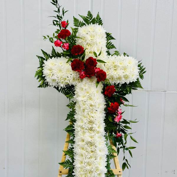 White floral cross on a wooden easel with red carnations