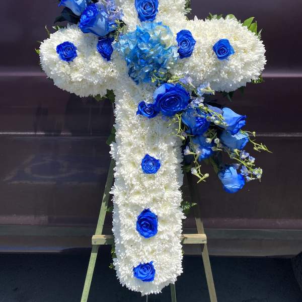 Cross-shaped floral tribute with white chrysanthemums and blue roses