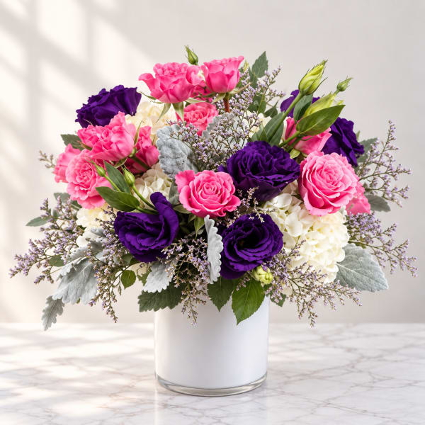Pink and purple flower arrangement in a white vase