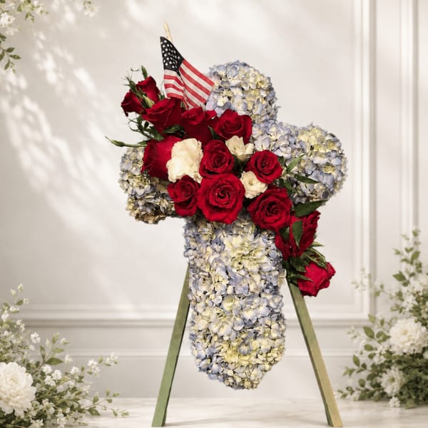 Red roses and pale blue hydrangeas arranged in a cross on an easel