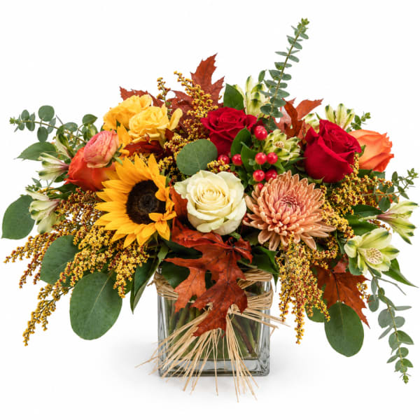 Autumn bouquet with roses, sunflower, chrysanthemum, and a glass vase