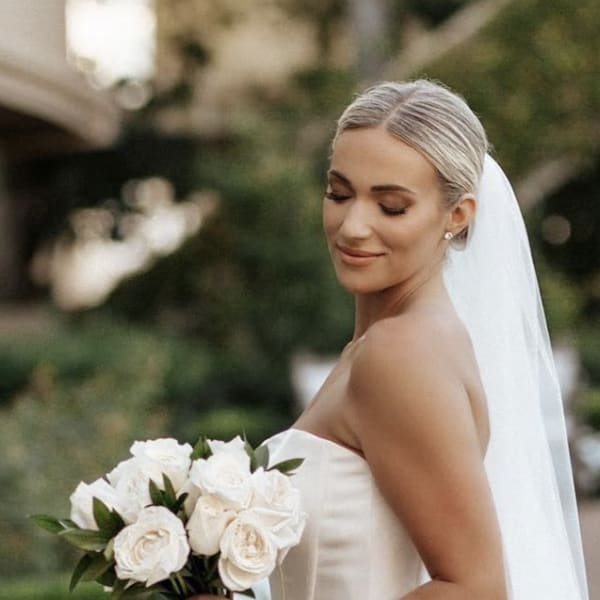 Bride holding a bouquet of white roses in a strapless gown