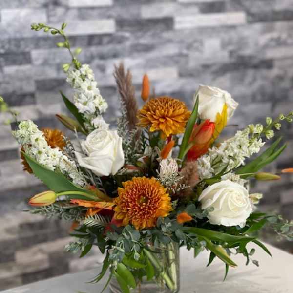 Mixed bouquet of white roses and orange chrysanthemums in a glass vase