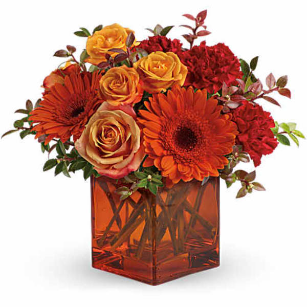 Orange and red flowers arranged in a square amber vase