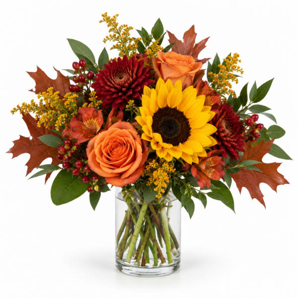 Autumn bouquet of sunflowers, roses, and mums in a clear glass vase