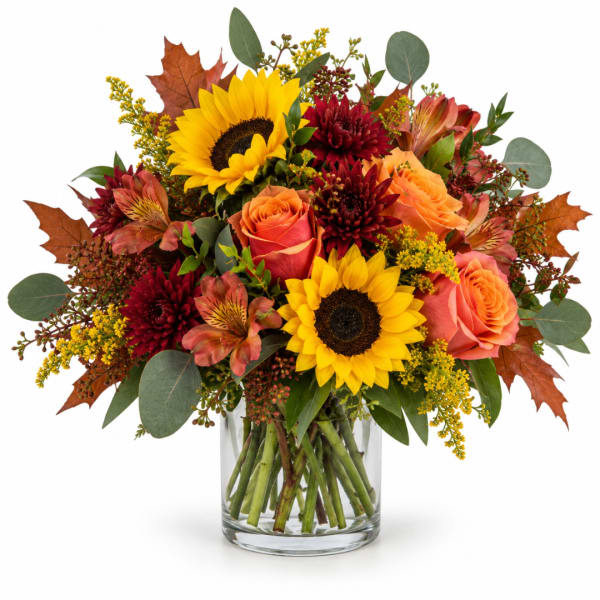 Bouquet of sunflowers, roses, and autumn flowers in a clear glass vase
