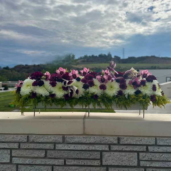 Long floral centerpiece with white and purple blooms on a metal stand