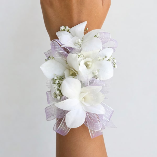 White floral wrist corsage with lavender ribbon on an arm
