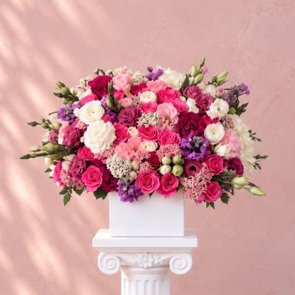 Large pink, white, and purple rose arrangement in a white box