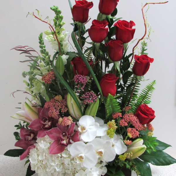 Red roses with white orchids and pink flowers in a rectangular container