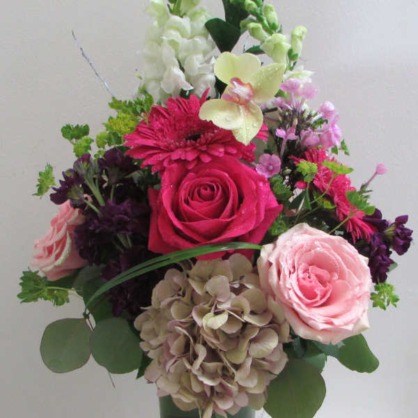 Mixed pink and white flowers arranged in a tall glass vase