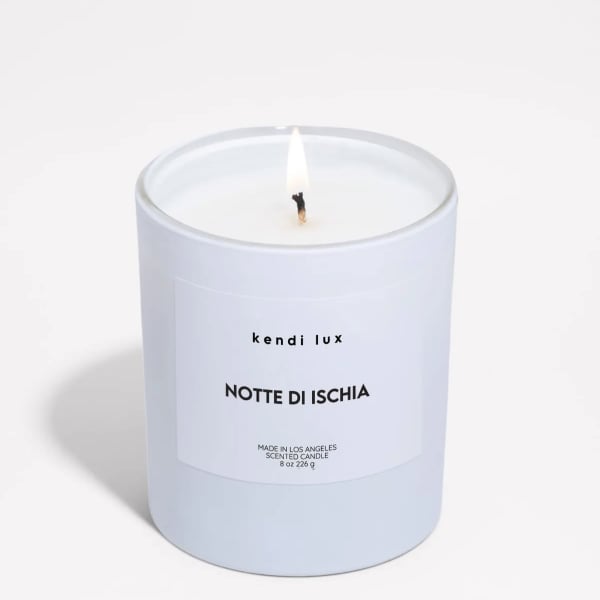 Lit white scented candle in a frosted glass jar