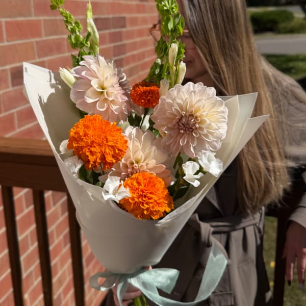 Bouquet of pale pink and orange flowers wrapped in white paper
