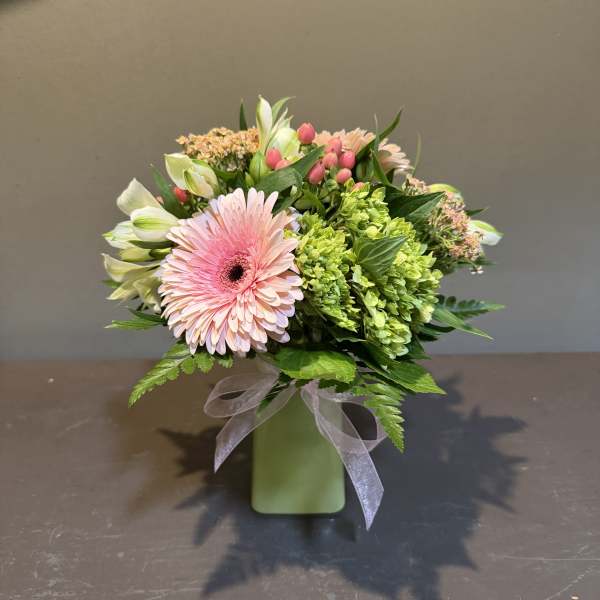 Pink gerbera bouquet in a green vase with a ribbon