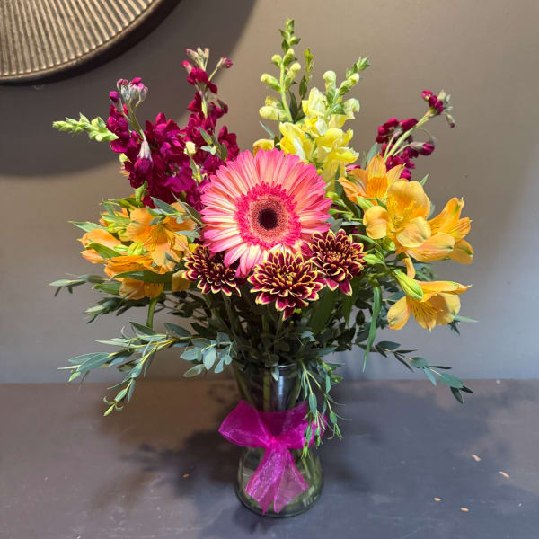 Mixed bouquet with a pink gerbera daisy in a glass vase