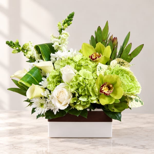 Green and white floral arrangement in a rectangular box with orchids, roses, and hydrangeas