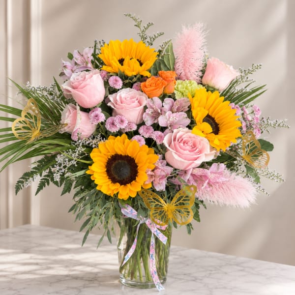 Bouquet of sunflowers and pink roses in a clear glass vase