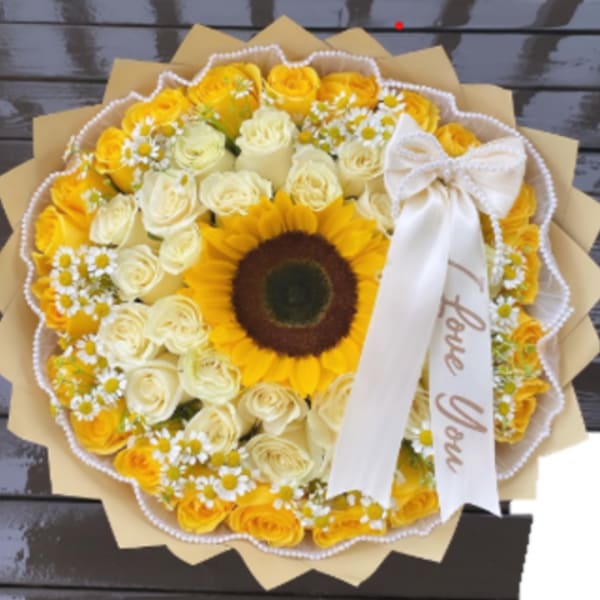 Round bouquet of yellow and cream roses with a sunflower center and white ribbon