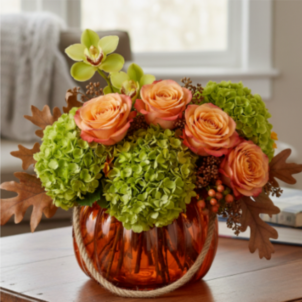 Low orange glass pumpkin vase with peach roses, green hydrangeas, and a green orchid bloom