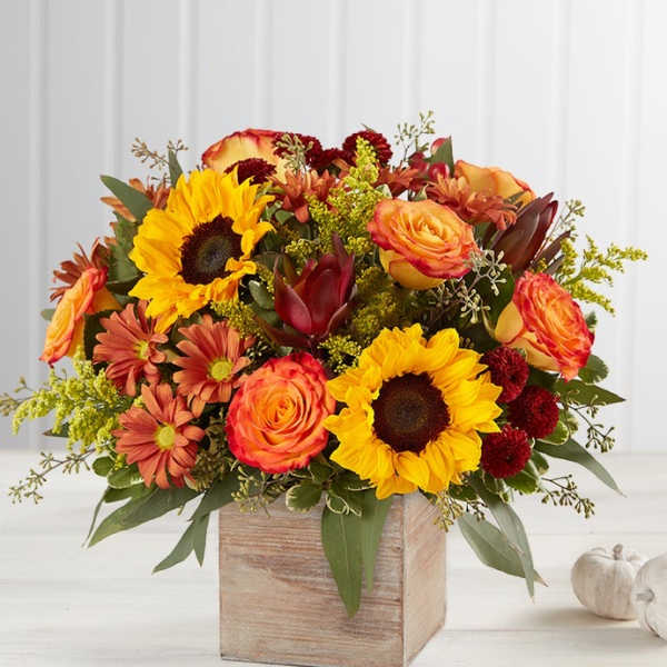 Sunflowers and orange roses in a wooden cube vase