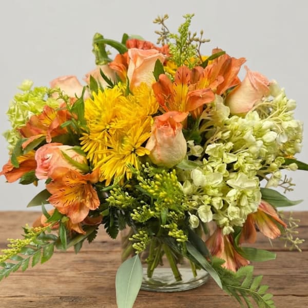 Orange and yellow mixed bouquet in a clear glass vase