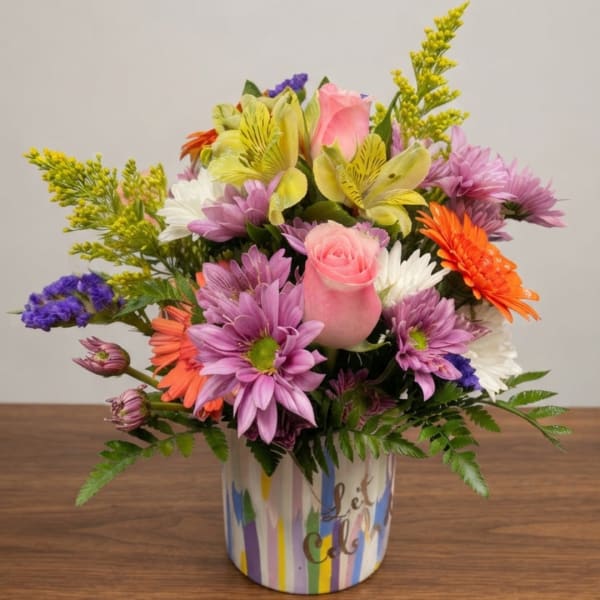Mixed bouquet of pink, purple, yellow, and orange flowers in a striped container