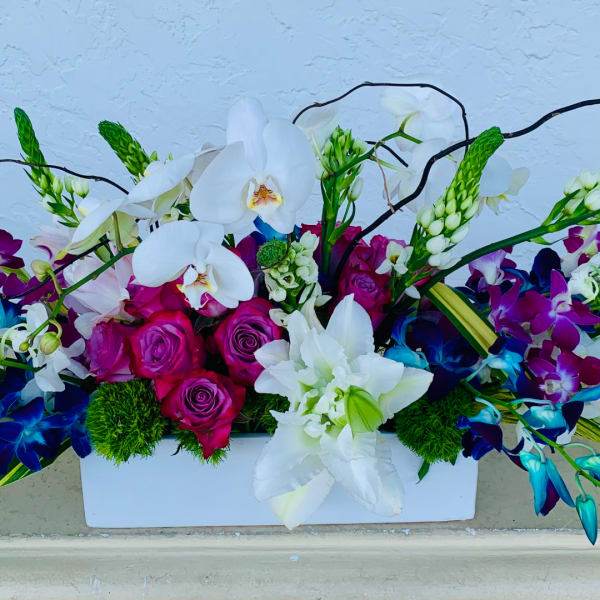White orchids and magenta roses in a white rectangular vase