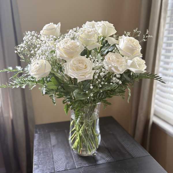 White roses arranged in a clear glass vase with baby's breath