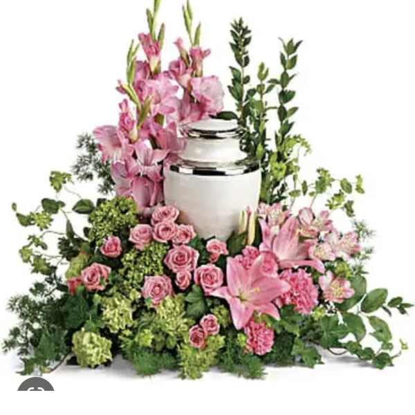 Pink flowers arranged around a white urn with greenery