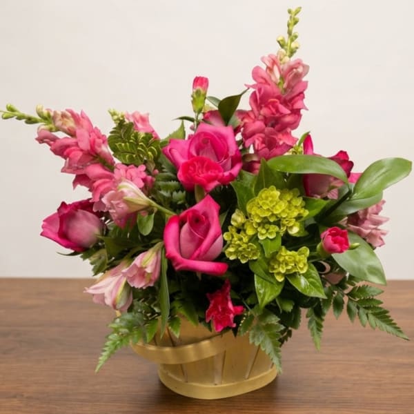 Pink roses and snapdragons arranged in a gold basket