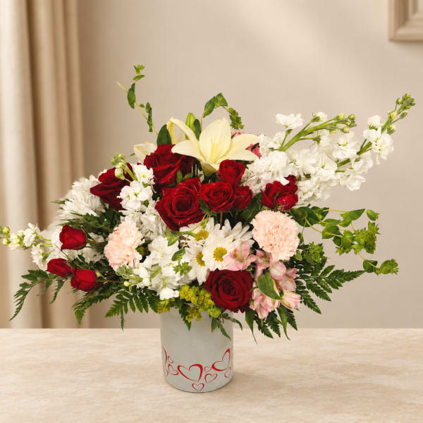 Mixed bouquet of red and white flowers in a heart-decorated vase