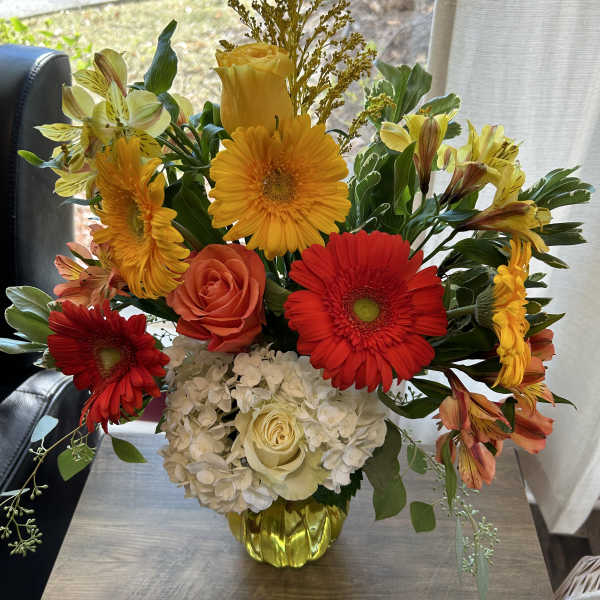 Bright mixed bouquet in a yellow vase with red, orange, and white flowers