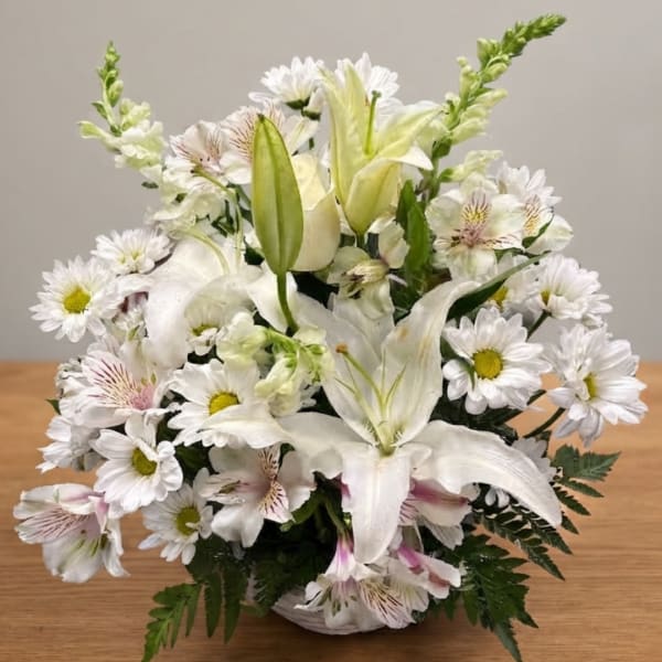 White floral arrangement with lilies, daisies, and alstroemeria in a low container