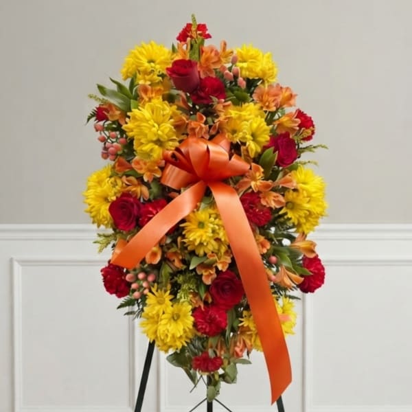 Bright floral standing spray with yellow and red flowers and an orange ribbon
