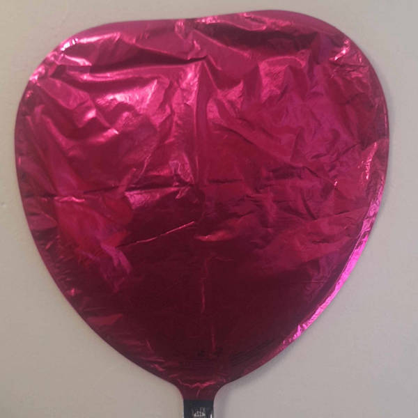 Pink heart-shaped foil balloon on a plain background