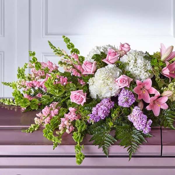 Pink and white floral casket spray with lilies, roses, and hydrangeas